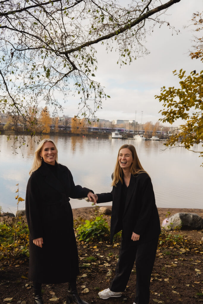 VD Visionite Helsingfors Silja Alvik, till vänster, står tillsammans med Maiju Virta, till höger, framför en sjö en höstdag och ler in i kameran