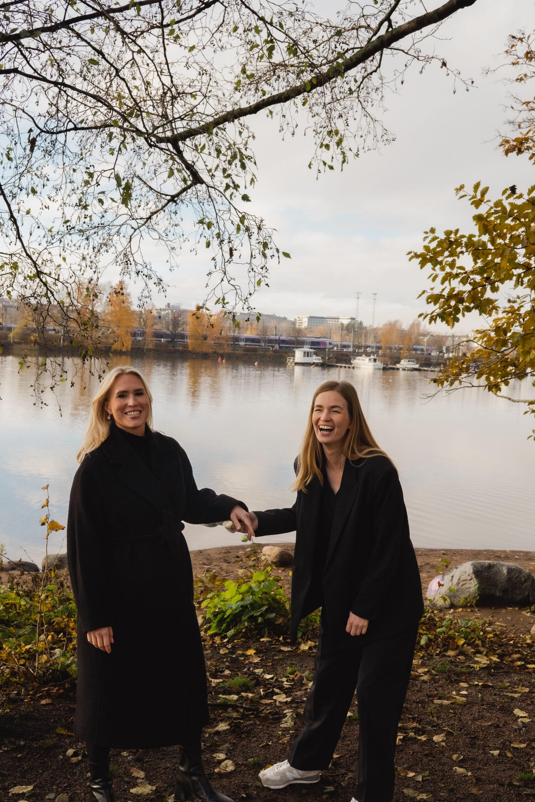 VD Visionite Helsingfors Silja Alvik, till vänster, står tillsammans med Maiju Virta, till höger, framför en sjö en höstdag och ler in i kameran